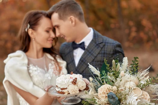 bride and groom on the nature in autumn . wedding couple with cake outdoor