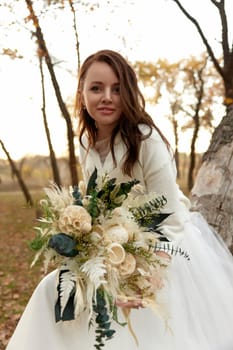 beautiful happy bride holding wedding autumn bouquet in nature