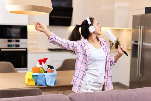 young happy housewife woman singing and cleaning her home, girl enjoying domestic work.