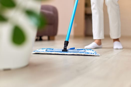 young woman cleaning and mopping floor at living room, daily housekeeping , Cropped