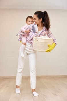 happy mother housewife is holding cute baby girl and basket with laundry , Happy family