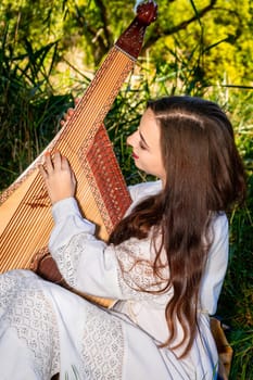 A young bandura player plays the bandura in nature.