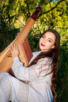 A bandura player plays the bandura on a sunny summer day.