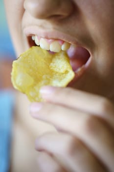 Closeup of unrecognizable teenage girl eating crunchy potato chip at home