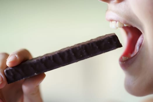 Closeup of crop anonymous teenage girl with mouth open about to eat healthy nutritious protein bar at home