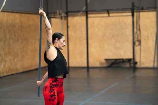 Side view horizontal photo with copy space of a mature fit woman stretching with a bar in a gym