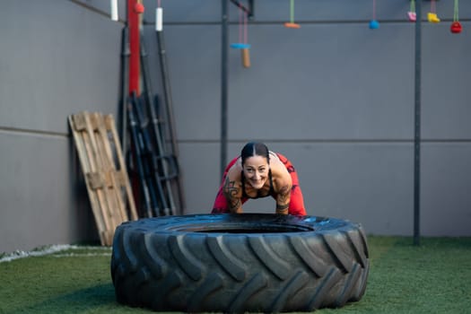 Sportive mature woman flipping a huge wheel in a cross training gym