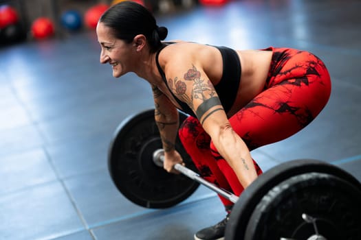 Smiling mature sportive woman weightlifting in a cross training gym