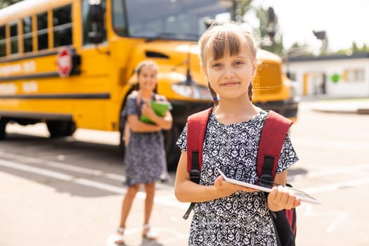 Portrait of two girls with school bags after lesson in school.