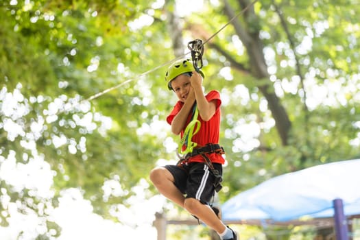 Cute school boy enjoying a sunny day in a climbing adventure activity park.