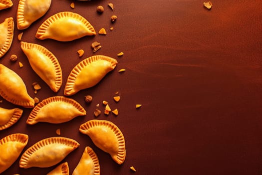 Golden baked empanadas on dark surface with spices scattered around.