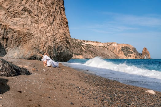 Woman beach white dress flying on Wind. Summer Vacation. A happy woman takes vacation photos to send to friends