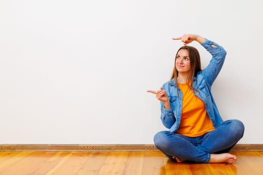 Woman in jeans and denim jacket gesturing at blank space, ideal for advertising.