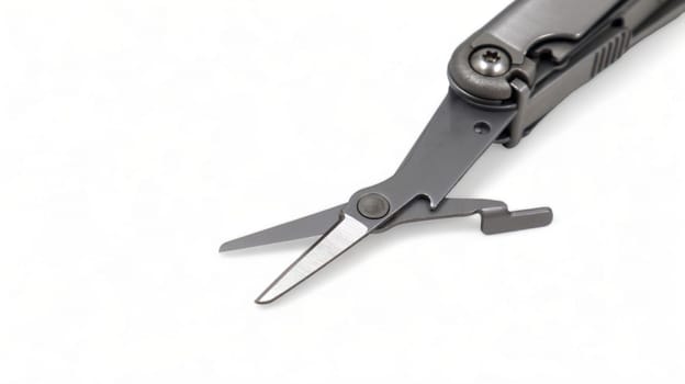 The scissors tool is pulled out of the multitool. Modern steel multitool with many tools isolated on white background. Compact and portable product. Pocket knife. EDC concept. Copy space