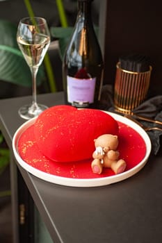 Heart Shaped Red Velvet Valentine's Day Cake with a bottle of sparkling wine and a glass in a restaurant. High quality photo