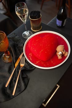 Heart Shaped Red Velvet Valentine's Day Cake with a bottle of sparkling wine and a glass in a restaurant. High quality photo