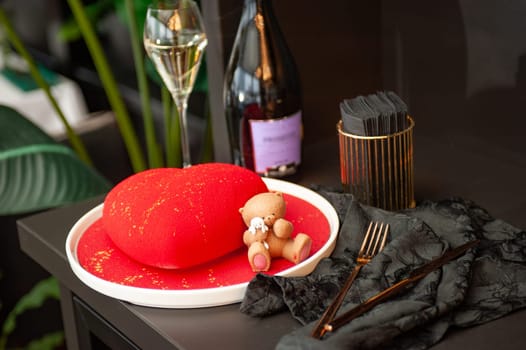 Heart Shaped Red Velvet Valentine's Day Cake with a bottle of sparkling wine and a glass in a restaurant. High quality photo