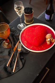 Heart Shaped Red Velvet Valentine's Day Cake with a bottle of sparkling wine and a glass in a restaurant. High quality photo