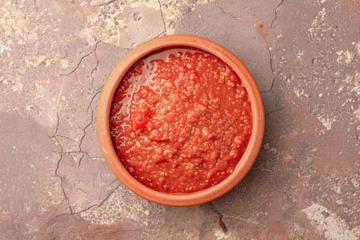 Harissa sauce, traditional in the Maghreb countries, made from hot red pepper, garlic and spices in a bowl on the surface of a natural stone.Top view.