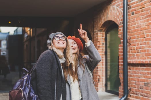 Young pretty girls friends having fun outdoor in autumn evening in city laughing and going crazy on the street - friendship and funny people