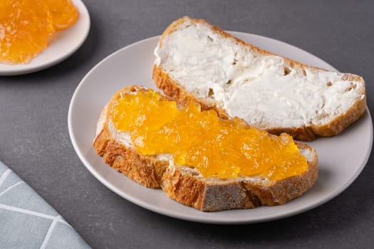 Sandwiches with apricot jam and butter on a gray background.