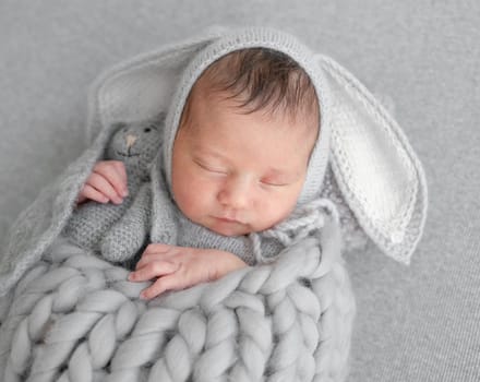Newborn Girl In Bunny Hat Sleeps During Baby Photo Session In Studio