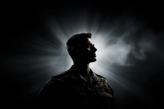 Silhouette of a male soldier on a dark background with bright rays.