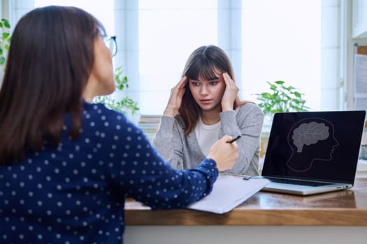 Sad, serious teenage girl at a session in the office of a mental professional, psychologist, counselor, social worker. Feelings, difficulties, problems, depression, stress, youth concept