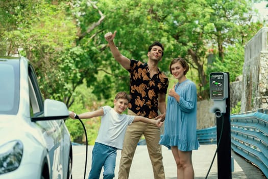 Family road trip vacation with electric vehicle, lovely family recharge EV car with green and clean energy. Natural and eco friendly car travel for sustainable environment. Perpetual