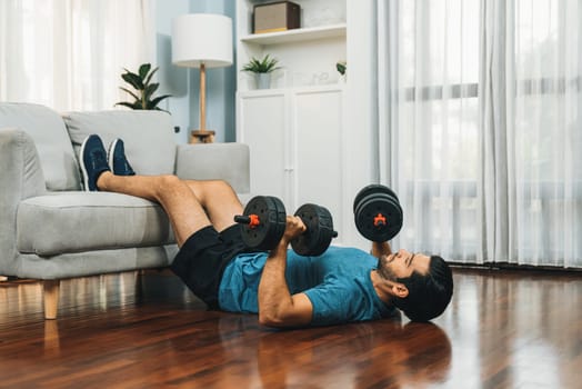 Athletic body and active sporty man using furniture for effective targeting muscle gain with weight lifting dumbbell exercise at gaiety home as concept of healthy fit body home workout lifestyle.