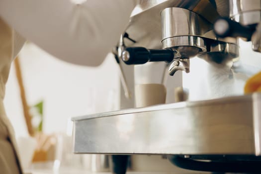 Close up of female barista making coffee in a coffee machine working in cafe. High quality photo