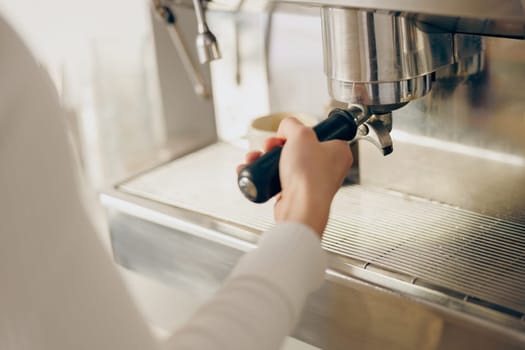Close up of female barista making coffee in a coffee machine working in cafe. High quality photo