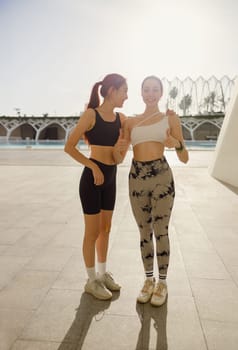 Two young female sportswomen have a rest after morning jogging outdoors. High quality photo