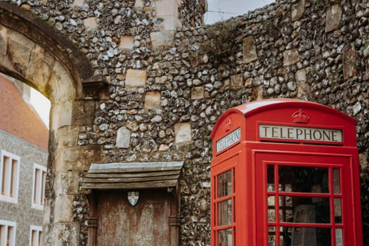 The red telephone booth against a medieval stone wall