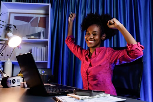 Working African woman with happy glowing, smiling face, getting new job project with good deal or marketing course scholarship information on laptop screen. Concept of cheerful expression. Tastemaker.