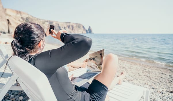 Digital nomad, Business man working on laptop by the sea. Man typing on computer by the sea at sunset, makes a business transaction online from a distance. Freelance, remote work on vacation