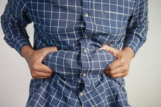 man's hand holding excessive belly fat, overweight concept.