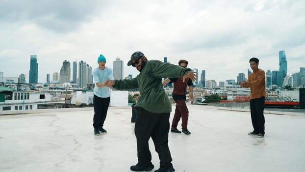 Professional break dance team practice B-boy dance while multicultural friends at rooftop. Young modern dancing group doing hip hop movement. Style,fashion,action. Outdoor sport 2024. Endeavor.