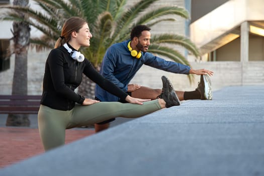 Young multiracial couple stretching leg before running, training outdoors. Copy space. Fitness and relationships.
