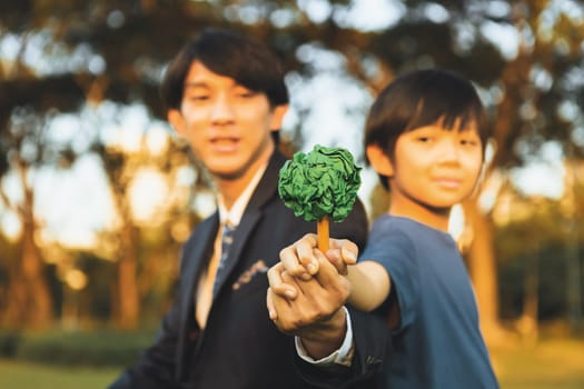 Asian boy and businessman holding paper tree together as Earth day concept as corporate social responsible to make greener environmental protection for sustainable future generation. Gyre