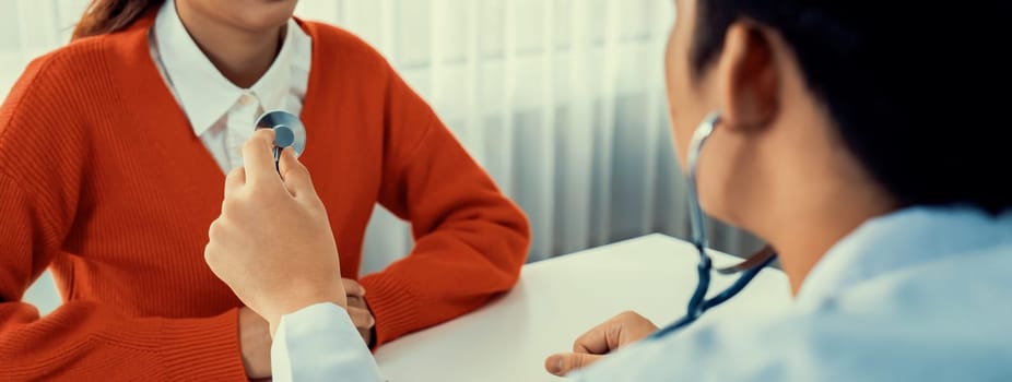 Patient attend doctor's appointment at clinic or hospital office. Doctor examining and diagnosis symptoms while checking the patient's pulse with stethoscope. Panorama Rigid