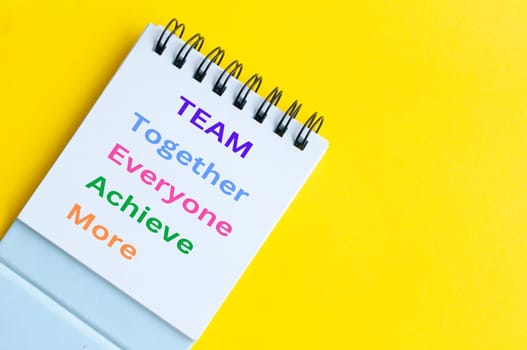 Team representing together, everyone achieve more. Team word on notepad on yellow background.