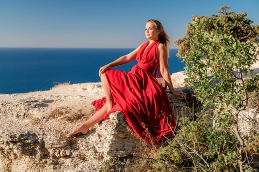 A woman in a red flying dress fluttering in the wind, against the backdrop of the sea