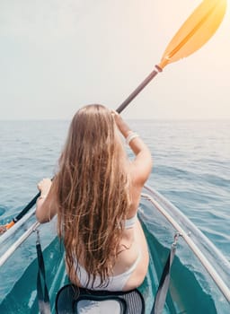 Woman in kayak back view. Happy young woman with long hair floating in transparent kayak on the crystal clear sea. Summer holiday vacation and cheerful female people having fun on the boat.