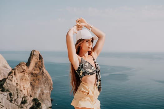 Woman travel sea. Happy tourist taking picture outdoors for memories. Woman traveler looks at the edge of the cliff on the sea bay of mountains, sharing travel adventure journey.