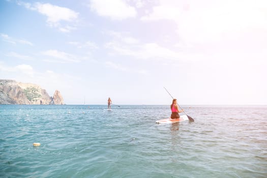 Woman sup yoga. Happy young sporty woman practising yoga pilates on paddle sup surfboard. Female stretching doing workout on sea water. Modern individual female outdoor summer sport activity