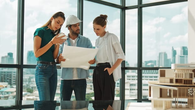 Professional architect engineer team talking, sharing, brainstorming about design while manager hold at project plan. Young architect holding plan while manager listen and point at plan. Tracery