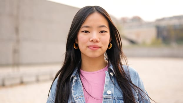 Asian young woman looking at camera in the street