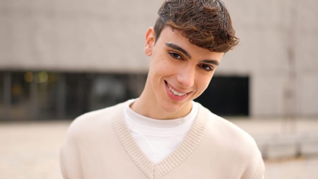 Cool caucasian young man looking at camera and smiling outdoors