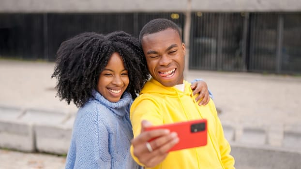 An african couple taking a selfie in a urban park